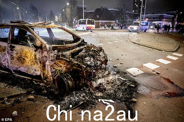 现场有一辆被烧毁的汽车,两群厄立特里亚人在此发生打斗