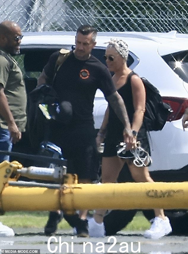 Pink,真实姓名为 Alecia Beth Moore,穿着休闲黑色背心、黑色短裤和白色运动鞋