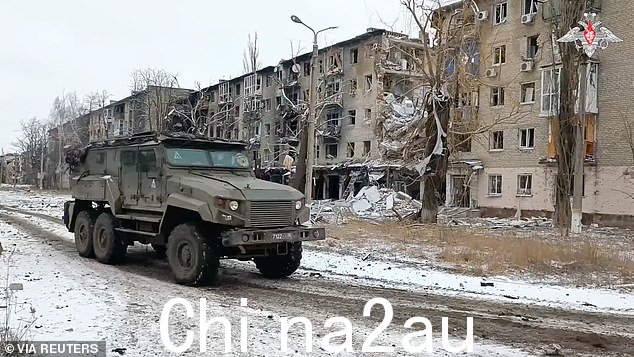 一辆俄罗斯军车驶过顿涅茨克地区阿夫季夫卡镇在俄乌冲突中受损的居民楼,这张图片取自俄罗斯发布的视频2024 年 2 月 20 日