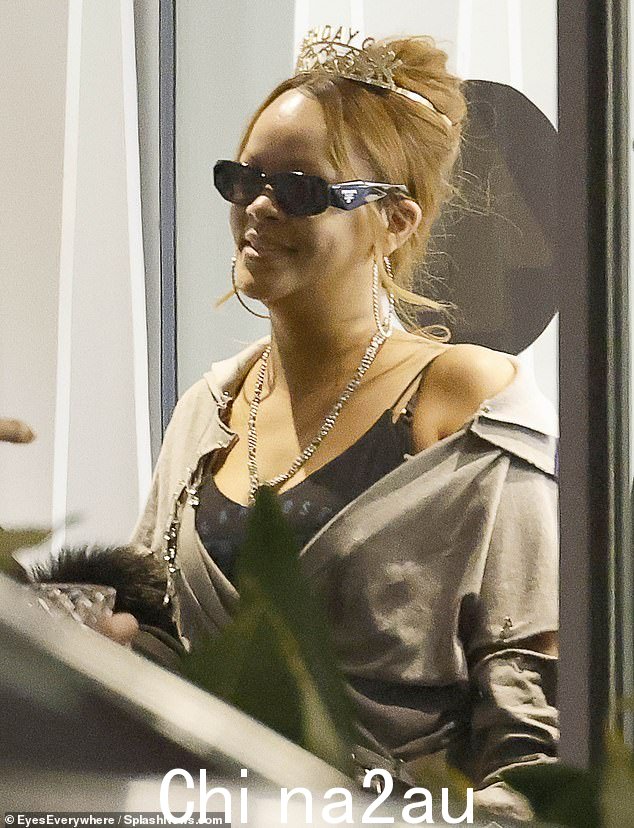 Rihanna 还穿着无袖黑色上衣搭配多层灰色毛衣,以及深黑色紧身裤和金色高跟鞋