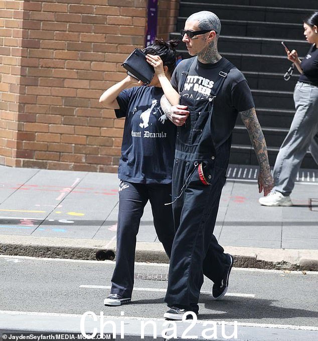 Travis,48 岁,穿着黑色图案 T 恤,搭配深色工装裤,看起来很休闲,与他妻子的情绪风格相呼应