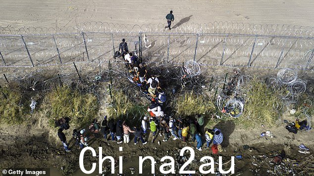 鸟瞰图,移民在 3 月 13 日穿越美国和墨西哥边境时穿过铁丝网