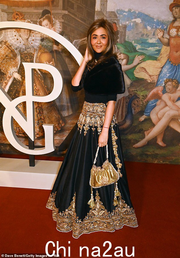 Aarti Lohia 身穿黑色和金色印度风格服装,搭配金色包袋,展现出令人瞠目结舌的表演
