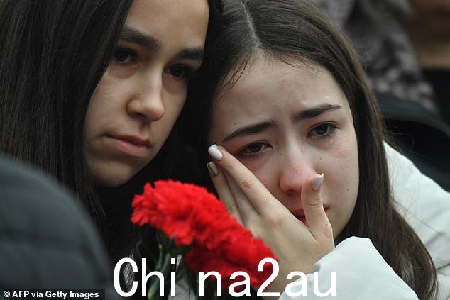 一名妇女在与其他哀悼者聚集在番红花市政厅前时擦干眼泪