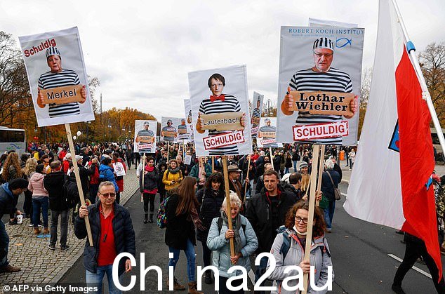 示威者举着标语牌,标语牌上有(从左到右)德国总理安格拉·默克尔、社民党政治家卡尔·劳特巴赫和罗伯特·科赫研究所 (RKI) 所长洛塔尔·维勒,上面刻有“有罪”字样。 2020 年 11 月 18 日,抗议德国政府为限制新型冠状病毒传播而采取的措施