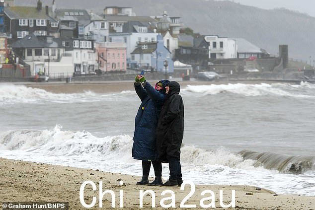今天尼尔森风暴期间,一对夫妇在多塞特郡莱姆里吉斯的海滩上自拍