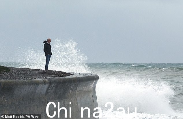 今天早上,一名男子观看海浪冲击康沃尔郡西顿的海堤