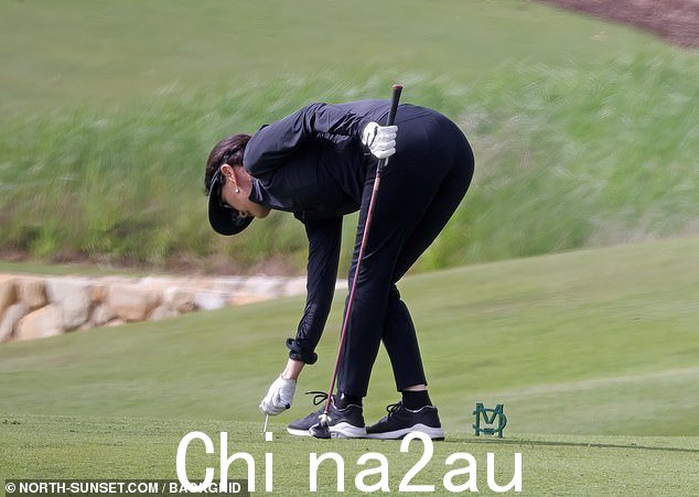 她似乎正在将高尔夫球座放在地上