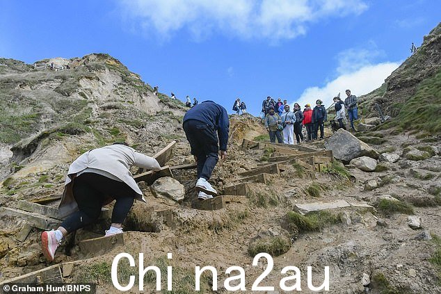银行假日周末,度假者爬上危险的悬崖,以避免在多塞特郡 Durdle Door 山体滑坡损坏的台阶上排队