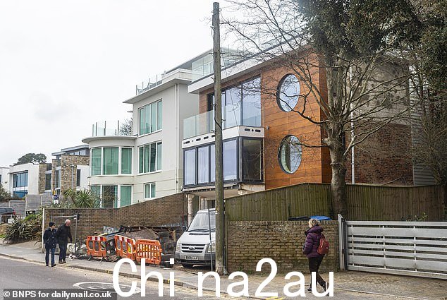建筑材料高高地堆放在房产前面的橙色工程围栏后面