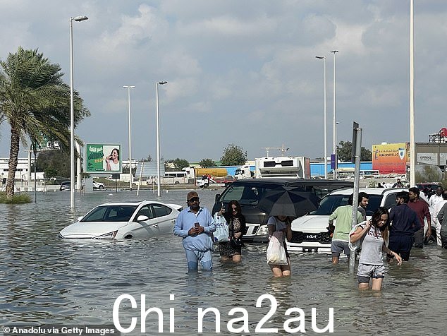 2024 年 4 月 17 日,阿拉伯联合酋长国迪拜,大雨对日常生活造成负面影响,人们涉水穿过被淹没地区的被淹没的街道