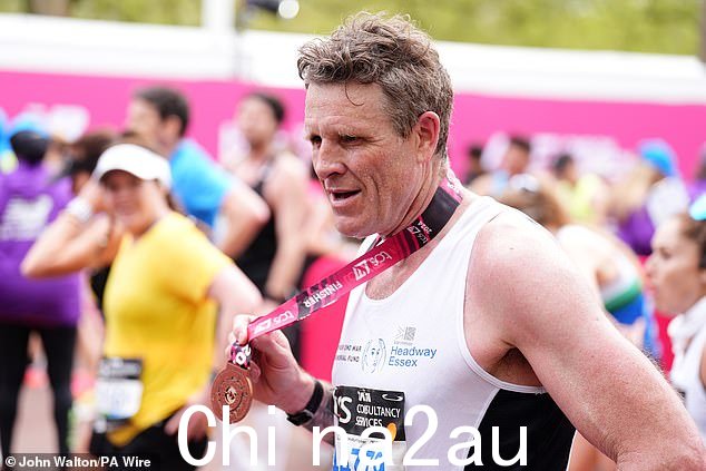 一位疲惫不堪的奥运选手 James Cracknell 在完成 TCS 伦敦马拉松后举起奖牌