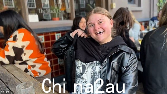 一位粉丝炫耀她的泰勒·斯威夫特 T 恤,她坐在黑狗外面的长凳上,享用一品脱啤酒