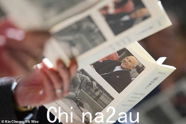 在今天的感恩节仪式上,一位会众拿着一份服务令,上面显示了前 F1 赛车手斯特林·莫斯的照片
