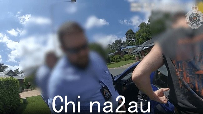 逮捕的视频显示,这名 34 岁的男子穿着深色背心和裤子,被护送进一辆没有标记的警车。图片:昆士兰州警察。