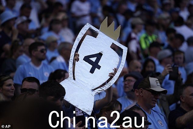 一名曼城球迷高举着英超联赛奖杯的纸板剪纸,中间有数字 4