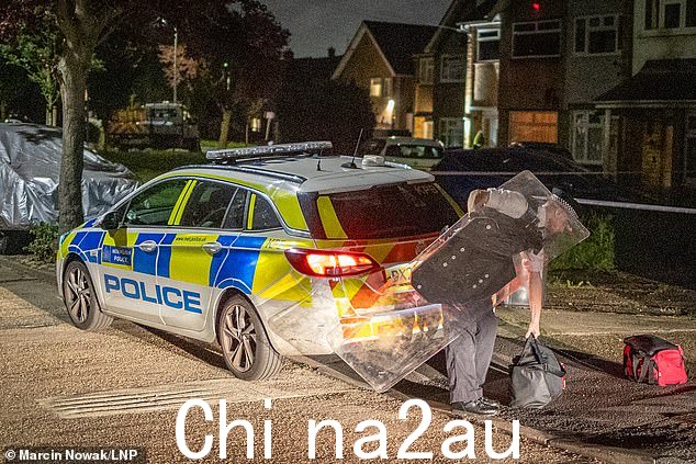 周一,一名警察在悲剧现场附近拿起盾牌