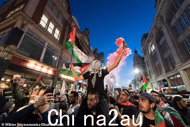 当反以色列示威者聚集在伦敦以色列大使馆外时,一名亲巴勒斯坦抗议者手持照明弹和旗帜