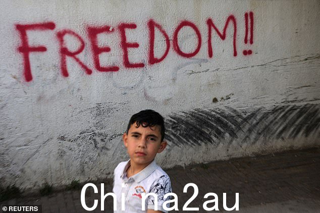 2024 年 5 月 15 日,以色列耶路撒冷东耶路撒冷 Silwan 区,一名巴勒斯坦儿童站在喷漆墙前