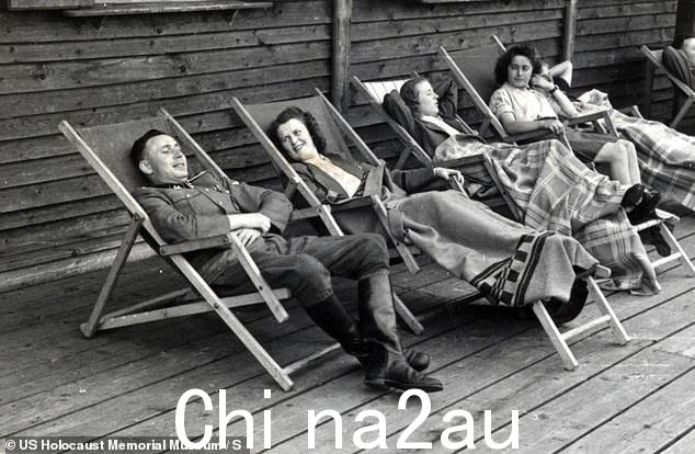 二战期间,一名纳粹军官和一群妇女在奥斯威辛集中营附近的躺椅上休息