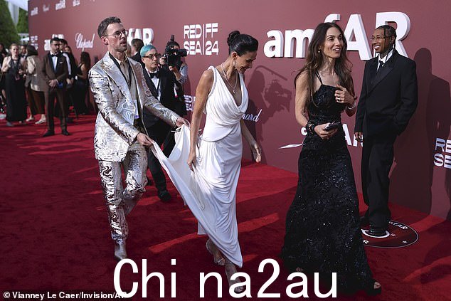 准备前往下一个拍照地点,好莱坞著名造型师 Brad Goreski 身着时髦的银色西装,为 Demi 的拖尾拖着,让她可以快速移动