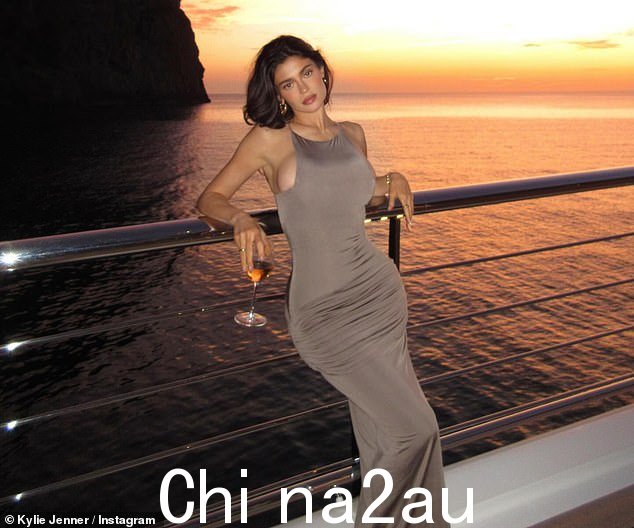 Jenner 设计了一件几乎遮盖胸部的灰褐色挂脖长裙,这件连衣裙的褶皱紧贴着她的臀部,凸显了她的背部曲线