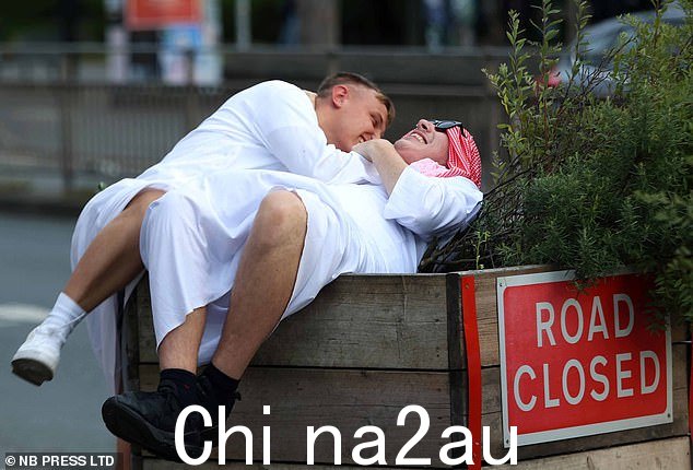 两个朋友在庆祝 2023 年 8 月夏季最后一个银行假日时掉进花盆里咯咯笑