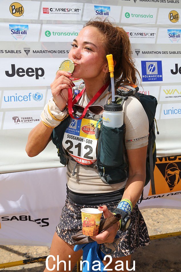 Susie 在另一场 Marathon des Sables 赛事的终点线亲吻她的奖牌,感到自豪但又疲惫不堪