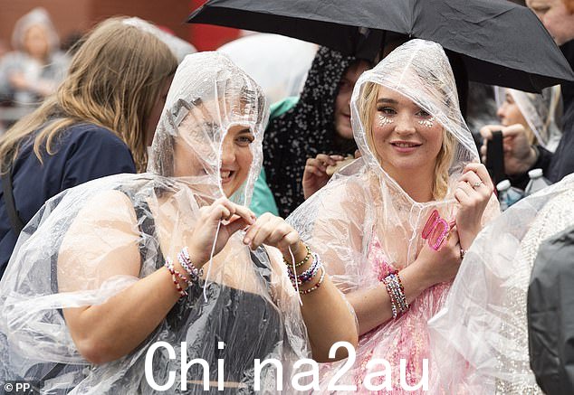 两位泰勒·斯威夫特粉丝冒着雨,穿着斗篷来保护他们的主题服装