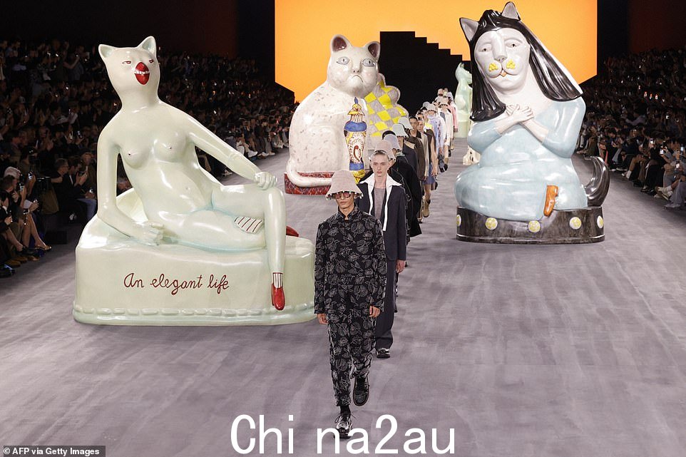 模特们走上跑道,周围环绕着巨大的猫形雕像