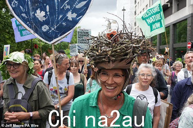 示威者在伦敦市中心的恢复自然抗议期间游行。抗议者举着横幅和标语牌,其中一人甚至戴着鸟巢自行车头盔
