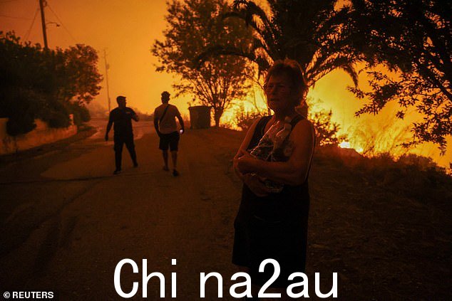 2024 年 6 月 21 日,希腊南部拉塔斯村,一名当地居民在野火旁拿着瓶装水