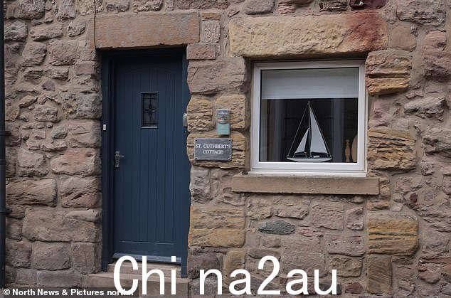 一座石头小屋,窗户上有一件帆船艺术品