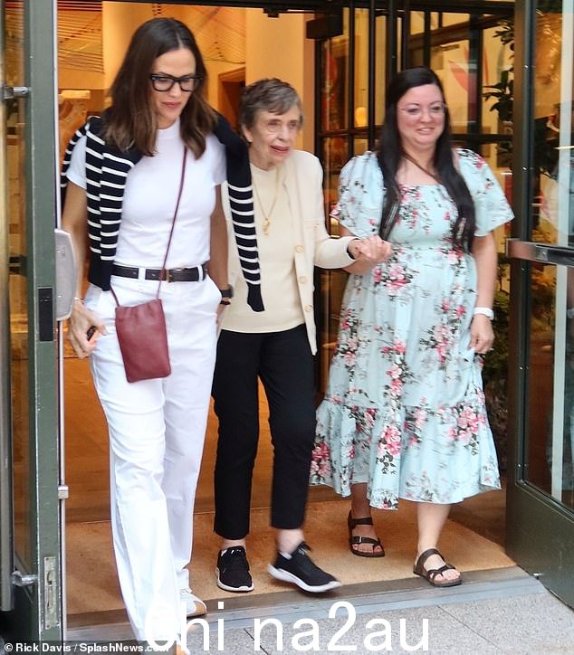 Pat,86 岁,与她的女儿搭配奶油色毛衣和衬衫,搭配黑色长裤,齐脚踝