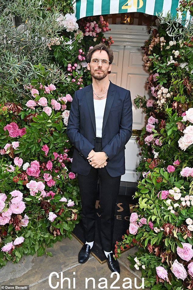 Sam Claflin,38 岁,穿着蓝色西装外套、白色 T 恤和黑色长裤