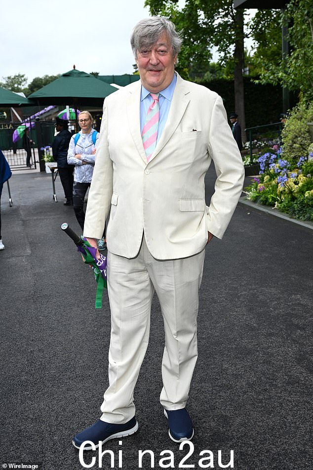 Stephen Fry 身穿奶油色西装,搭配蓝色衬衫和蓝色和粉色条纹领带,身材魁梧