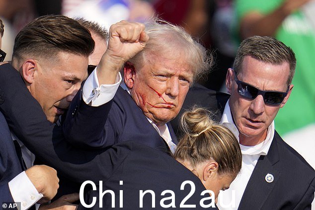 特朗普从西装特工的掩护下出现,举起拳头,大喊:‘战斗,战斗,战斗’,然后被送往医院” class=