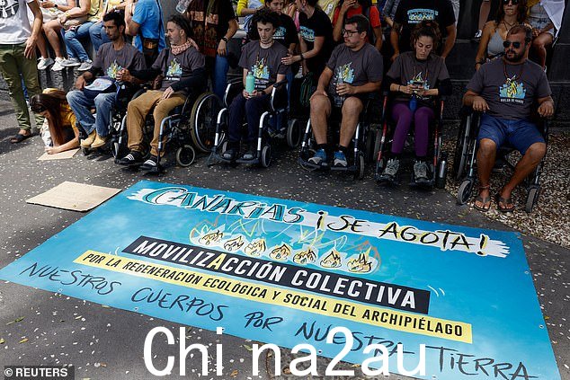 人们在4 月,在西班牙圣克鲁斯-德特内里费加那利群岛抗议旅游模式改变时,绝食坐在轮椅上