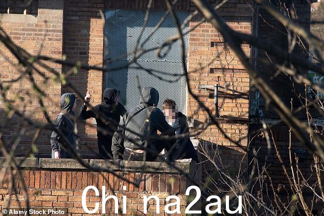 穿着连帽衫的十几岁男孩从一家封闭酒店的屋顶露台扔石头