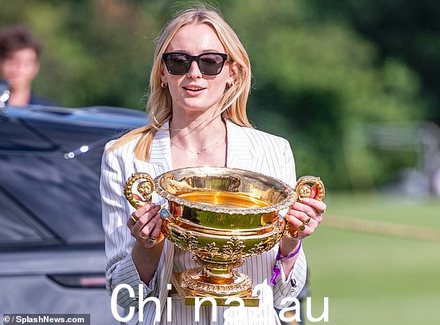 当这位明星在豪华车前举起金杯时,一群围观者向她微笑