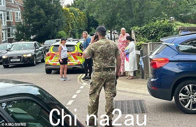 周二晚上,一名身穿军装的男子在吉林汉姆警察警戒线旁打电话