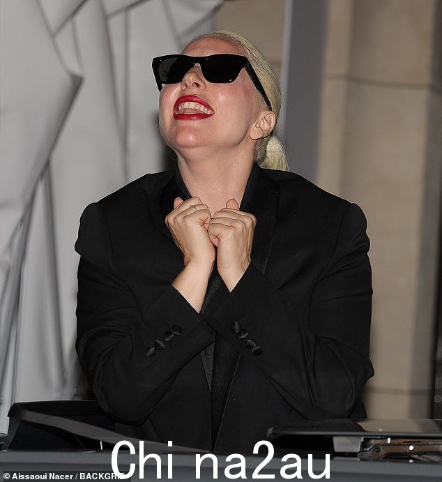 Lady Gaga 选择不佩戴任何华丽的珠宝,但在嘴唇上涂了大胆的红色,为单色外观增添了一抹流行色彩