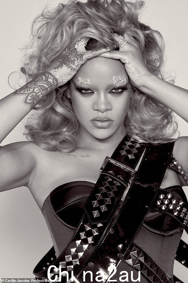 换个角度看,蕾哈娜 (Rihanna) 穿着黑色紧身胸衣,肩上挂着两条镶有饰钉的黑色腰带