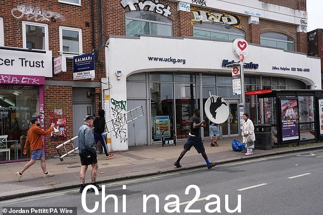 一名穿着黑色 T 恤和短裤的男子拿着这件艺术品走在街上