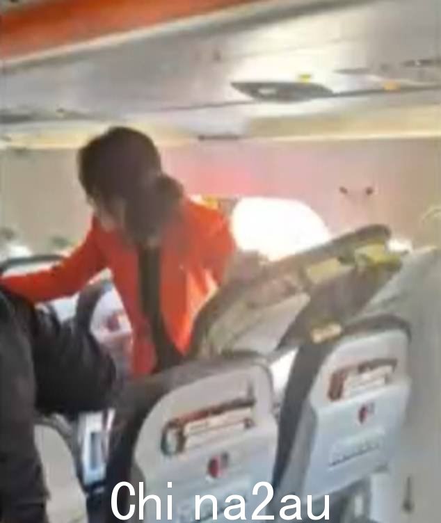 一名乘客跳出紧急出口后,一名捷星航空乘务员在紧急出口旁拍照