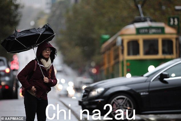 维多利亚州警告,当低压槽经过东南部时,强烈的雷暴即将来临(如图,墨尔本中央商务区一名妇女奋力撑着雨伞)