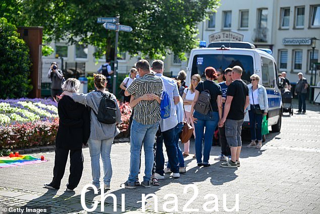 哀悼的人们站在昨天致命刺伤现场附近,导致三人死亡、八人受伤