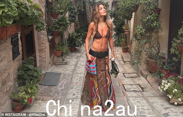 她再次展示了她健美的腹部,穿着棕色比基尼上衣和及地裙子,在胸部下露出了一些