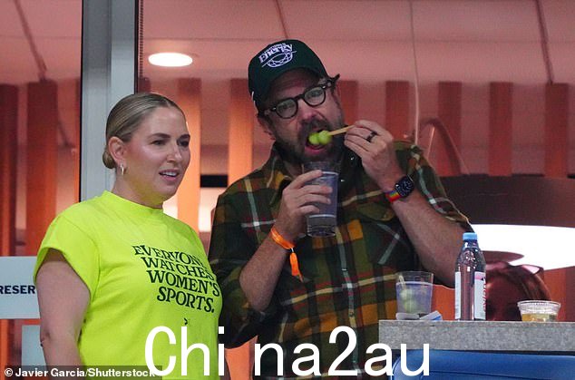 杰森在比赛中场休息时戴上森林绿色棒球帽,一边吃着瓜丸子