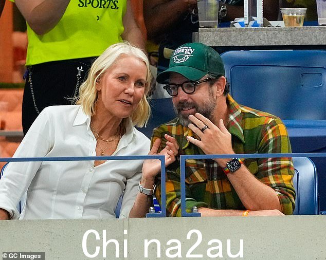澳大利亚网球教练 Rennae 在看台上与杰森聊天时,身着纹理白衬衫,佩戴一层金项链,展现出时尚的身材